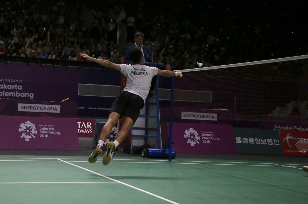 badmintonspelare som hoppar mot nätet med racket långt fram
